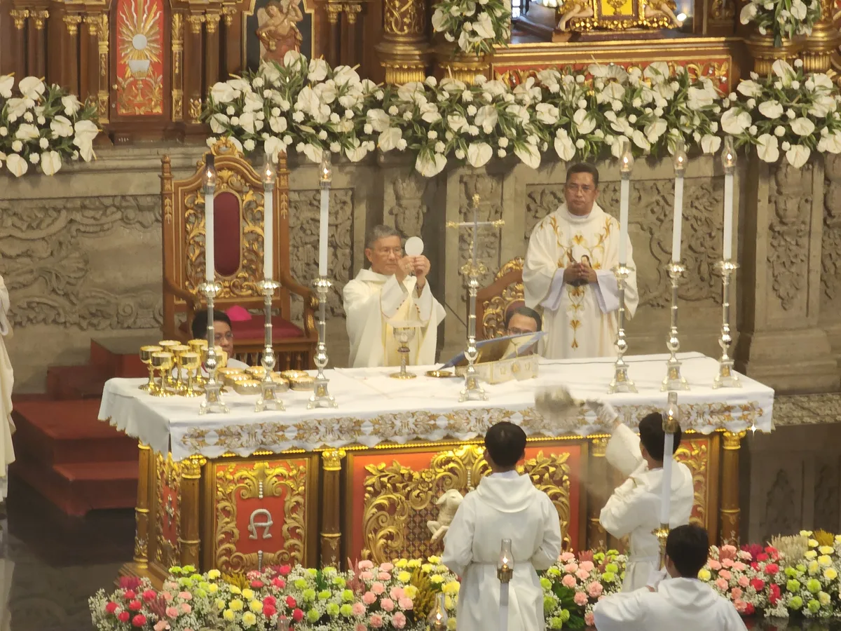 Bishop elevates the Eucharistic host during Mass before an ornate altar